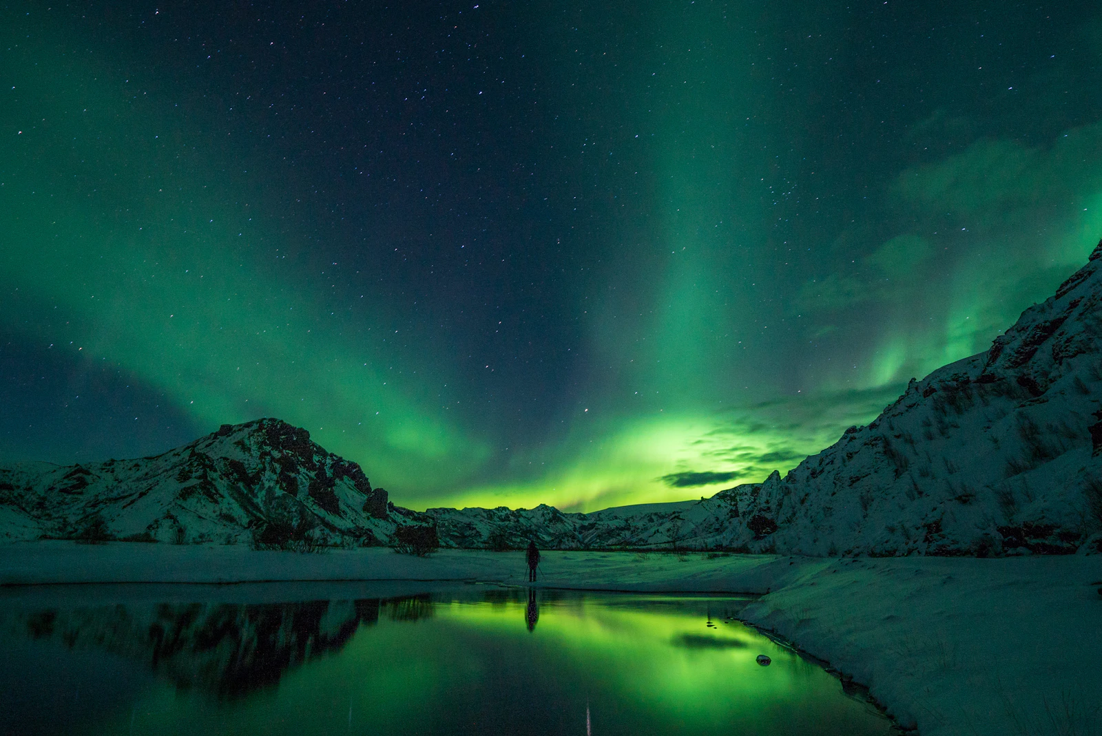 Northern lights above snowy mountains and lake in Thorsmork, Iceland