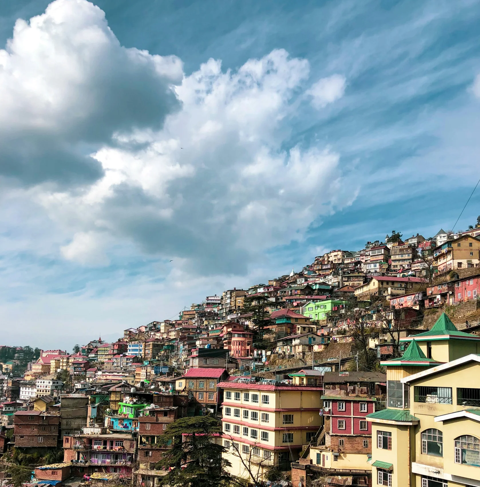 Colorful hillside houses in Shimla beneath a blue sky